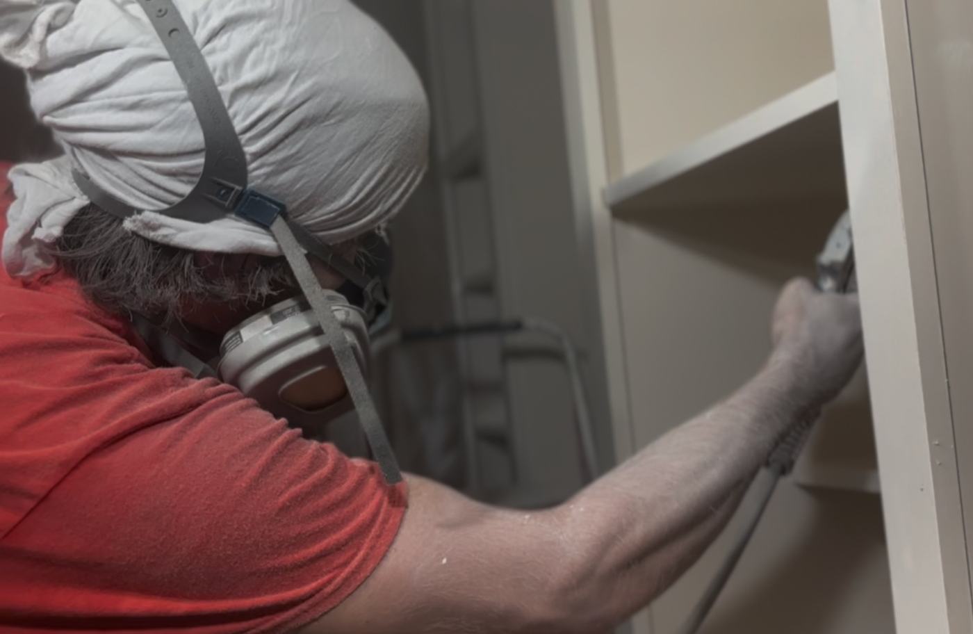 ACo. Painting spraying kitchen cabinet boxes with a fine-finish sprayer and respirator